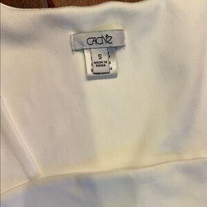 Cache Ivory  top . material is 97% nylon and 3% spandex. So it is form fitting.